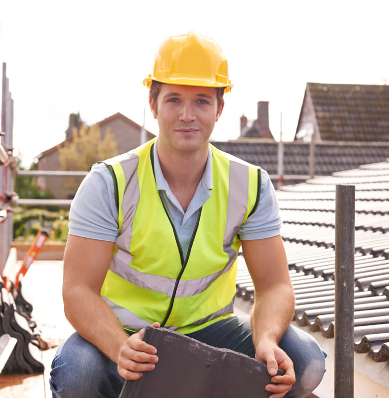 Roofer crouched down holding roof tile